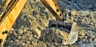 Bidding for the Position of Project Manager for the Construction and Completion of the Basseterre Desalination Plant Construction backhoe shovel moving heavy rocks and soil on a construction site. Overhead view